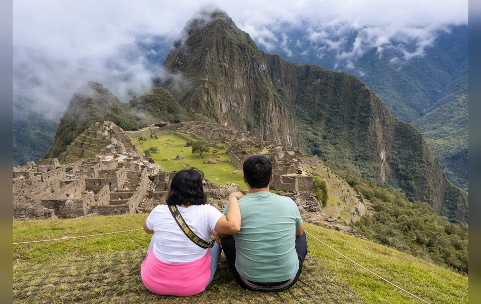 Couple sitting and admiring the panoramic view of Machu Picchu during their Peru vacation | Inca Culture Travel