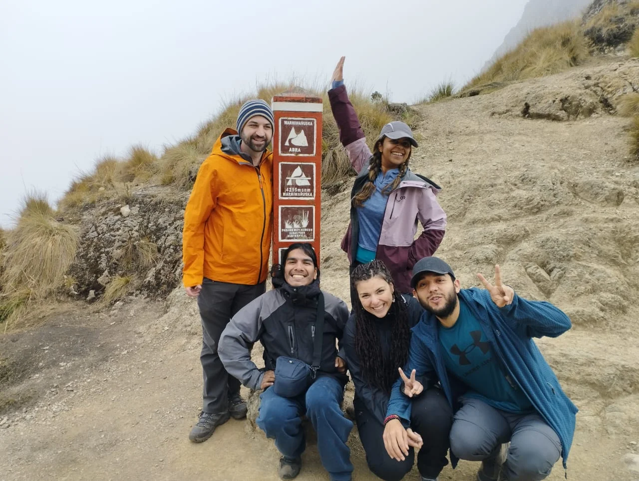 Tourists on the Inca Trail to Machu Picchu next to a trail sign, surrounded by mountains and Andean mist | Inca Culture Travel