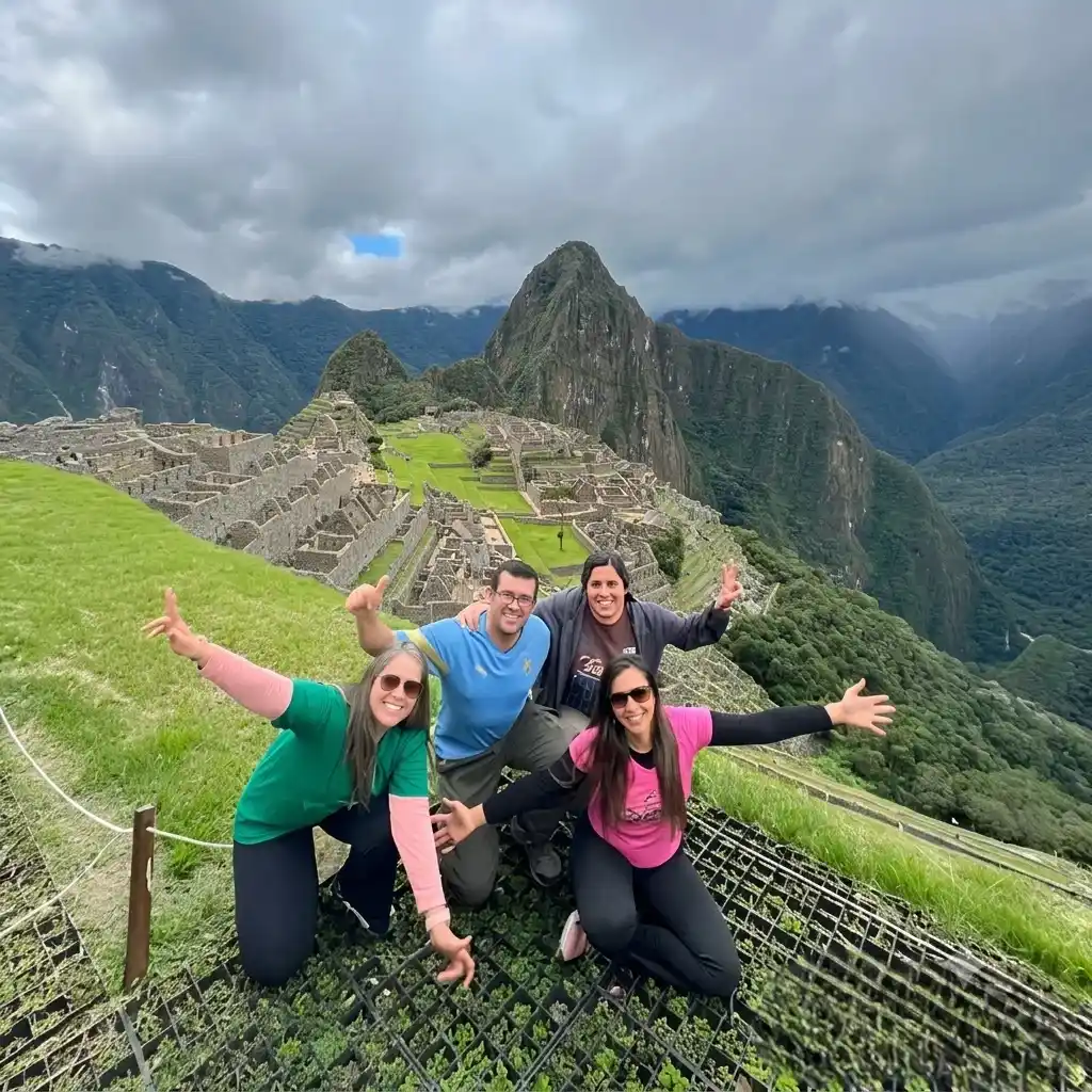 Group of happy friends posing with open arms at the classic overlook of Machu Picchu citadel in Peru | Inca Culture Travel