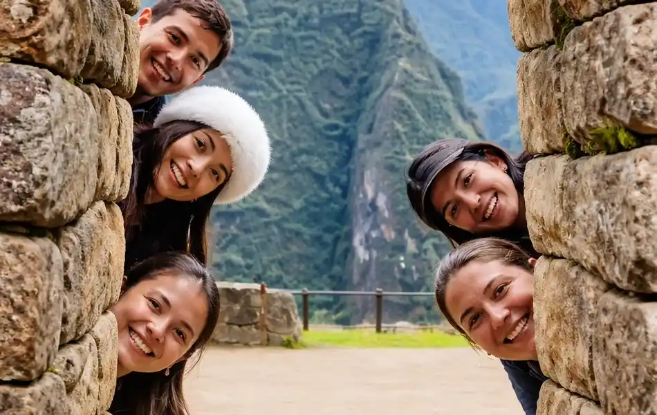 Group of friends smiling behind an Inca stone wall at Machu Picchu citadel | Inca Culture Travel