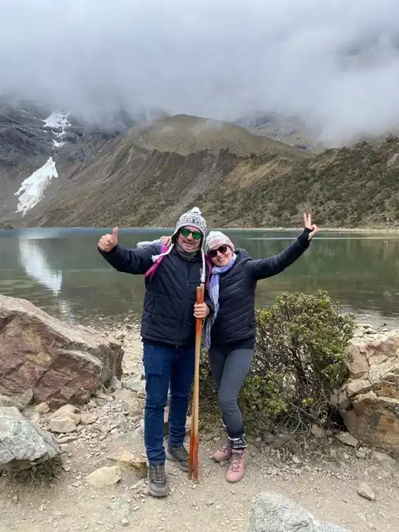 Group of tourists posing in front of Humantay Lagoon with mountainous landscapes and cloudy skies | Inca Culture Travel
